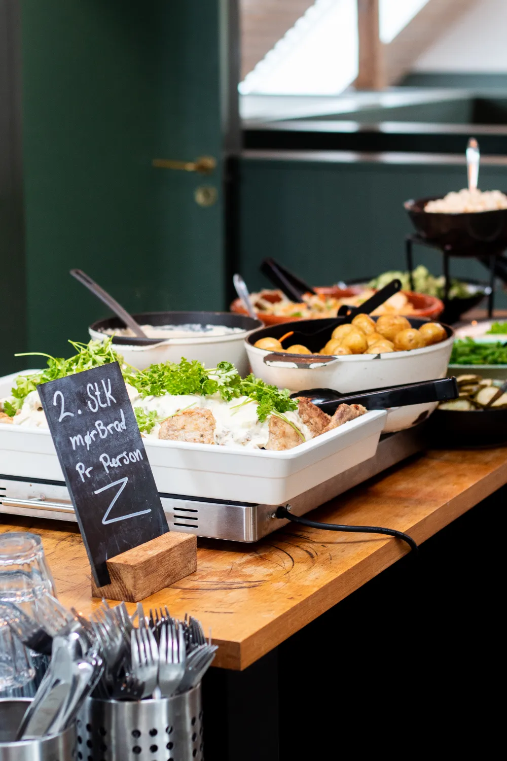 Professionel frokostordning til firmaer med varmholdt buffet, friske salater og hjemmebagt brød præsenteret med informative skilte